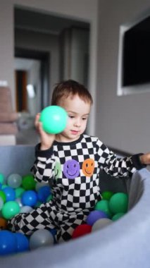 Oyunbaz küçük çocuk aktiviteler yapıyor. Komik çocuk renkli toplarla oynuyor..