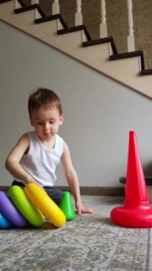 Renkli oyuncaklarla oynayan küçük sevimli çocuk. Çok mutlu bir çocuğun aktivitesi var. Dikey video.