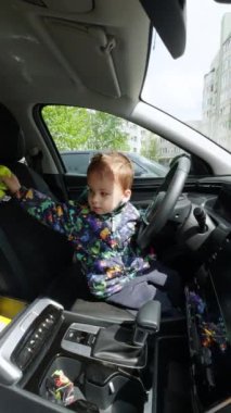 Direksiyon şakacı çocuk. Arabada oynayan küçük sevimli çocuk. Dikey video.