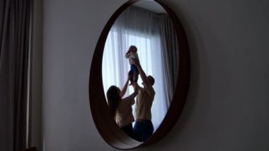 Mutlu aile çocuğu kaldırıyor. Küçük bebeği olan neşeli ebeveynler..