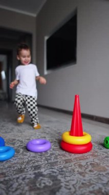 Küçük çocuğu oynayan renkli oyuncaklar. Oyun oynayan sevimli bir çocuk. Dikey video.