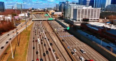 Atlanta şehir merkezindeki işlek geniş şeritli otobanlardan geçen birden fazla araç var. Güneşli bir günde şehrin manzarasına tepeden bak..