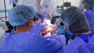 Beyin cerrahı ve yardımcı kadın doktor mikroskoba bakın. Sıhhiye, tıbbi aletler kullanarak beyin ameliyatı yapıyor..