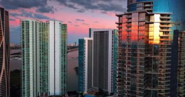 Güneşin batışını yansıtan cam pencereli güzel gökdelenlere yaklaşıyoruz. Miami, Florida, ABD. Güzel pembe mavi gökyüzü arka planda.