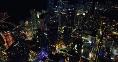 İnsansız hava aracı Miami, Florida, ABD şehir merkezindeki gökdelenlerin üzerine yavaşça iniyor. Şehir ışıkları tepeden.