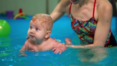 Annesi tarafından yüzme havuzunda tutulan sevimli sarışın oğlan. Anne çocuğuna doğduğundan beri yüzmeyi öğretiyor..