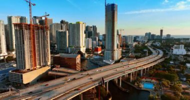 Miami şehir merkezindeki otobanlardan arabalar hızla geçiyor. Gün batımında tepeden güneşli şehir manzarası.