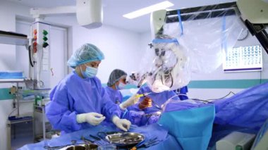 Kadın cerrahi asistanı enstrümanlarla masada duruyor. Doktor, cerrahın aldığı aletleri ve dezenfektanları verir..