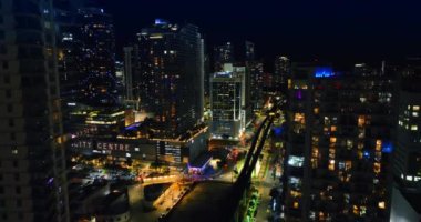 Gece şehrinin üstündeki gökdelenler arasında uçmak. Akşamları Miami, Florida 'nın aydınlık sokaklarının manzarası.
