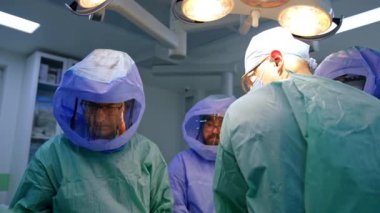 Koruyucu kask takan ve üniforma giyen tıbbi ekip travma cerrahisinde çalışıyor. Ortopedistler modern hastanede iş birliği yapıyorlar..