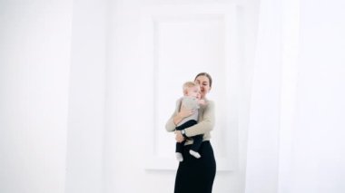 Gri kazaklı, uzun siyah etekli, sıska genç bir kadın elinde bir oğlan çocuğunu sallıyor. Anne ve çocuğu beyaz odada..