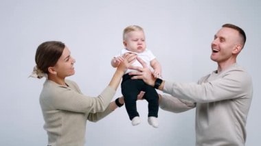 Mutlu ebeveynler bebeklerini iki taraftan tutuyorlar. Anne ve baba sevgili çocuklarını yanaklarından öpüyor..