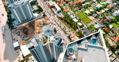 Miami Beach, Florida 'da trafiğin yoğun olduğu otobanın en üst görüntüsü. Güneşli sahil yakınlarında çalışan makineleri olan bir inşaat sahası..