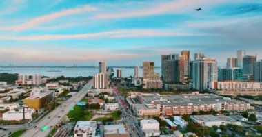 Yolcu uçağı Miami, Florida, ABD manzarası üzerinde uçuyor. Gün batımında şehir manzarası ve arka planda su manzarası.