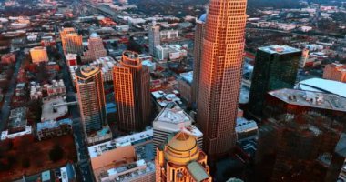 Gün batımında turuncu ışıkla aydınlatılan yüksek binalara yaklaşıyoruz. Charlotte şehir merkezi, NC, ABD Alacakaranlıkta.