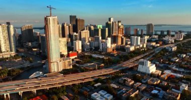 Gün batımında Miami 'nin güneşli cephelerinde. Şehrin yollarında birden fazla araba hareket ediyor. Hava perspektifi.