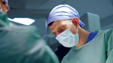 Ameliyat sırasında cerraha yardım eden maske ve şapka takan doktor bakışları. Düşük açı görünümü.