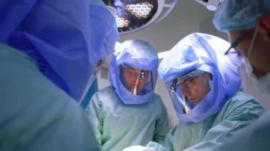 Ameliyat yapan bir grup erkek doktor. Travma operasyonunda odaklanmış profesyoneller işbirliği yapıyor..