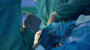 Lateks eldivenli tanınmayan doktor hastanın dizinde ameliyat yapıyor. Bazı aletler hastanın üzerinde..