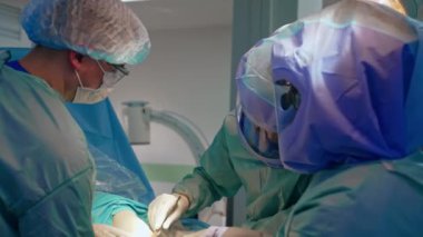 Diz üstünde travma ameliyatı yapan bir grup cerrah. Çalışan doktorların eşgüdümlü çalışmaları.