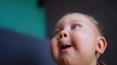 Beyaz, şirin, mavi gözlü bir bebeğin tombul yüzü. Kapatın. Kamerayı almaya çalışan meraklı çocuk..