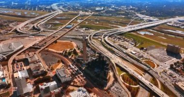Dallas, Teksas, ABD manzarasında birbirine dolanan ve kesişen birden fazla otoyol. Metropolün güneşli manzarası tepeden.