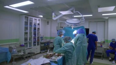 Cerrahlar modern ameliyathanede hasta ameliyat eder. Operasyonel tiyatronun kapısındaki pencerede görüntüler..