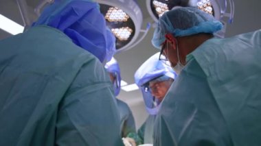 Koruyucu kask takan dört profesyonel sağlık görevlisi operasyon masasında çalışıyor. Kooperatif sağlık görevlilerinin görüş açısı düşük..