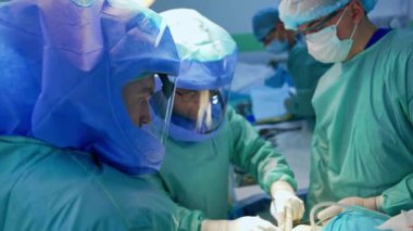 Deneyimli doktorlar travma cerrahisinde işbirliği yaparlar. Cerrah koruyucu miğferler üzerinde çalışıyor..