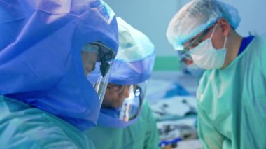 Koruyucu miğferli doktorlar travma geçiren hastaları ameliyat ederler. Sağlık görevlilerinin portresi ameliyata odaklandı.