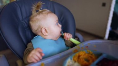 Yüzü lekeli küçük çocuk masada oturuyor. Sevimli çocuk annesinin elinden kaşığını alıyor..