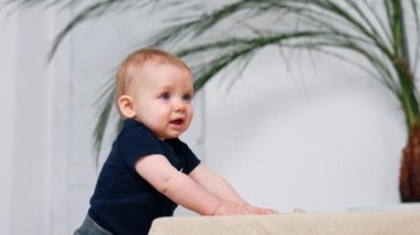 Kanepenin yanında duran kızıl saçlı sevimli çocuk. Küçük şirin bir bebek portresi..