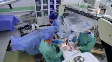 Doktor plastikle kaplı mikroskoba bakıyor. Bir elde modern mikro cerrahi operasyon. Üst görünüm.