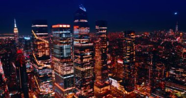 Geceleri ABD 'nin New York manzarasının üzerinde yükseliyor. Koyu mavi gökyüzünün arkaplanındaki parlak şehir manzarası.