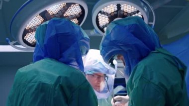 Koruyucu kasklı üç erkek cerrah operasyon için işbirliği yapıyor. Doktorlar işlerinde metal aletler kullanıyorlar..
