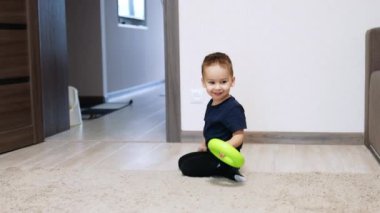 Enerjik beyaz bir çocuk odasında neşeli bir şekilde şarkı söylüyor. Mutlu çocuk elinde oyuncakla yerde sürünüyor..