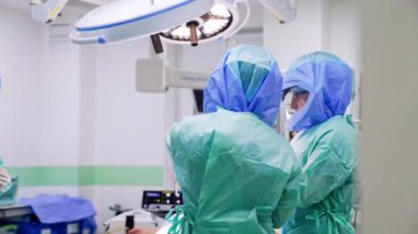 Bornoz ve koruyucu miğfer takan doktorlara uzaktan bakılıyor. Profesyonel cerrahlar modern hastanede ameliyata hazırlanıyorlar..