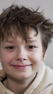 Kameraya bakan gülümseyen bir çocuğun portresi. Çocuk ellerini yüzüne koyar gözlük yapar ve yana döner. Kapatın. Dikey video