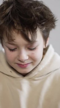 Kameranın önünde oturan yakışıklı ergen çocuk. Çocuk gözlerine mandalina koyuyor. Kapatın. Dikey video