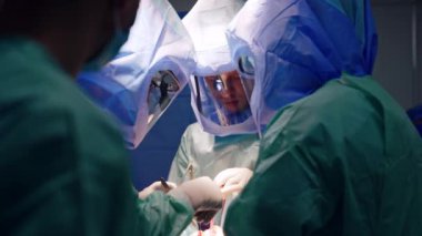 Ortopedik ameliyatı koruyucu kasklı erkek cerrahlar gerçekleştiriyor. Doktorlar modern cerrahi aygıt araçları kullanır.