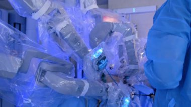 Steril estetik ameliyat yapan Massive Da Vinci robotu. Mavi üniformalı doktor laparoskopik araç kullanıyor.