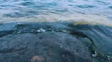 Kıyıya su sıçrıyor. Nehir ya da deniz kıyıdaki taşlara doğru geliyor. Üst görünüm.