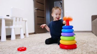 Neşeli bir şekilde oyuncak piramit inşa eden Kafkasyalı çocuk. Evde oynayan sevimli, gülümseyen bebek..