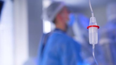 Ameliyathanede serum fizyolojik solüsyonu. Kapatın. Arka planda mavi üniformalı bir doktorun bulanık görüntüsü.