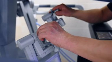 Beyaz erkek doktorların elleri robotik ekipmanların manipülatörlerini hareket ettirir ve döndürür. Da Vinci Cerrahi Sistemi operasyonu. Kapat..