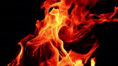 Sağa doğru uzanan şenlik ateşinin alevleri. Geceleri yanan kamp ateşinin izole edilmiş görüntüsü. Kapat..