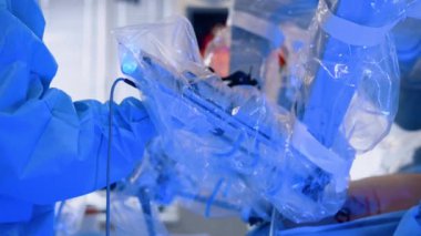 Da Vinci, hastanın karnındaki plastik hareketlerle kaplı cerrahi kol. Doktor 'un eli cihazı tutuyor. Modern laparoskopik işlem.