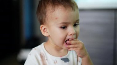 Güzel beyaz çocuk ahududu yiyor. Ağzının etrafında benekler olan şirin bir bebek annesinden böğürtlen alıyor ve ağzına koyuyor. Kapat..
