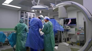 Ameliyat masasında ameliyat yapan iki cerrah var. Ameliyat hemşiresi aleti doktora veriyor..
