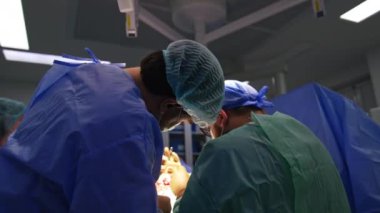 Yaralı uzuvları ameliyat eden iki beyaz cerrahın arka görüntüsü. Çalışkan tıp uzmanları travmaya karşı ameliyatlarda araç kullanırlar..
